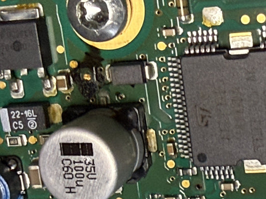 corroded circuit board inside a Mercedes SIM271 engine control module, close-up of leaked capacitor damage